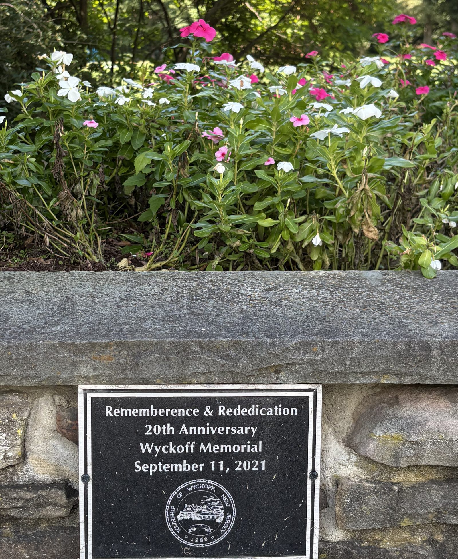 A small dark plaque set into a fieldstone wall, bearing the Township of Wyckoff seal and marking the 20th anniversary rededication of the Wyckoff Memorial on September 11, 2021.